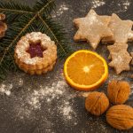 Foto mit Weihnachtskeksen, einem Tannenzweig, Nüssen und einer Orangenscheibe